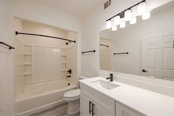 A white bathroom with a tub, toilet, sink, and mirror.